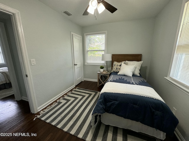 bedroom with dark wood-style floors, visible vents, ceiling fan, and baseboards