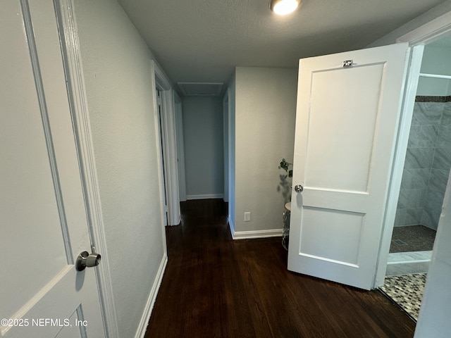 hall with baseboards, wood finished floors, and attic access