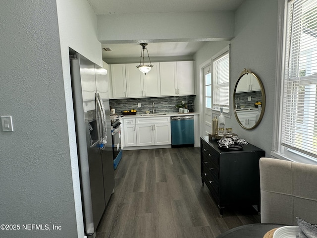 kitchen featuring tasteful backsplash, white cabinets, a sink, appliances with stainless steel finishes, and dark wood finished floors