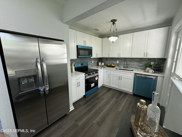 kitchen with appliances with stainless steel finishes, white cabinetry, light countertops, and backsplash