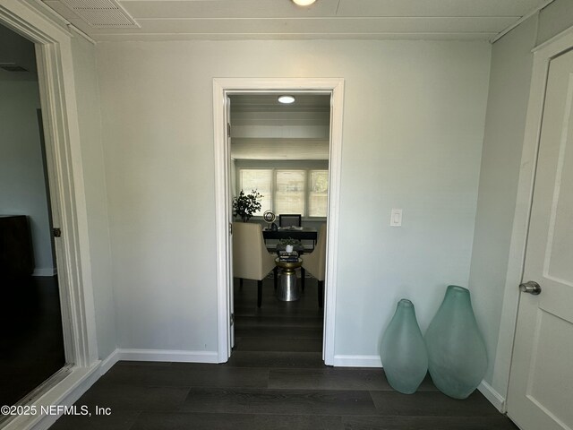 hall featuring visible vents, dark wood-style flooring, and baseboards
