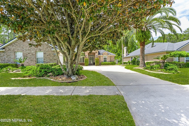 view of front of property with brick siding, a front yard, and concrete driveway
