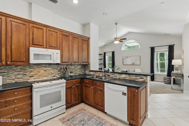 kitchen with a peninsula, dark countertops, a ceiling fan, and white appliances