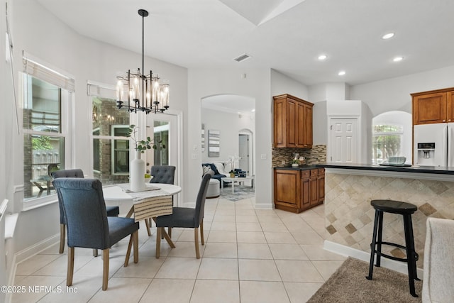 dining room with a healthy amount of sunlight, arched walkways, a notable chandelier, and visible vents
