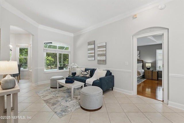 sitting room featuring crown molding, arched walkways, baseboards, and light tile patterned floors