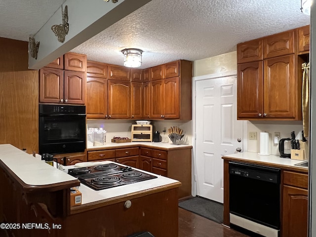 kitchen with black appliances, a textured ceiling, brown cabinets, and light countertops