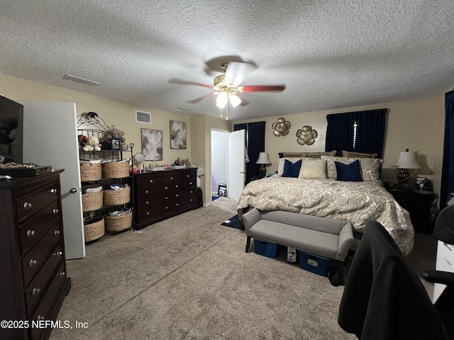 bedroom with a textured ceiling, visible vents, a ceiling fan, and carpet flooring