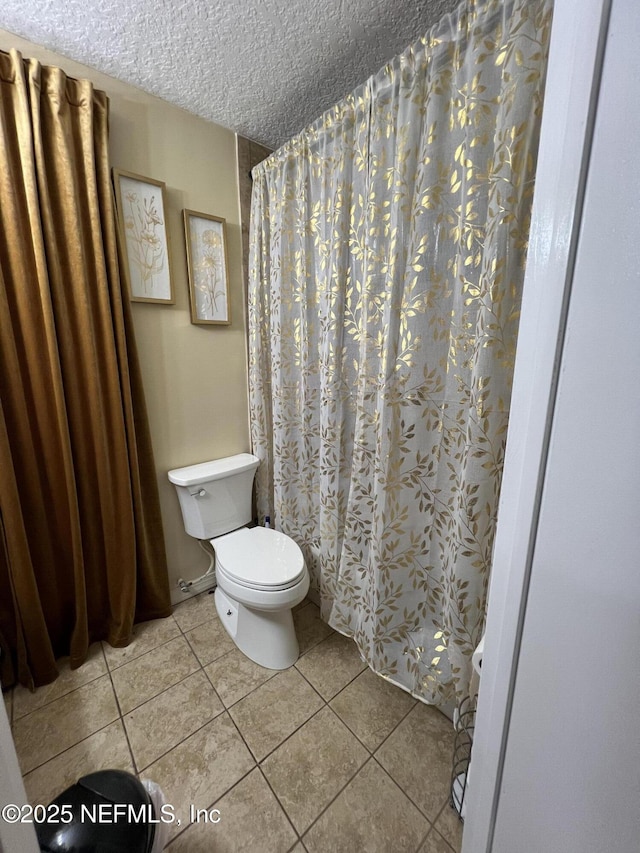 bathroom with tile patterned floors, toilet, a textured ceiling, and a shower with shower curtain