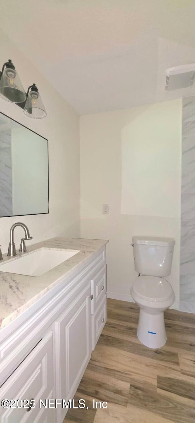 bathroom featuring toilet, wood finished floors, vanity, and baseboards