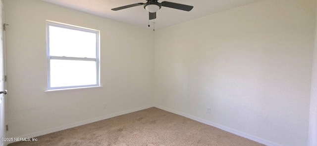 spare room with a ceiling fan, light colored carpet, and baseboards