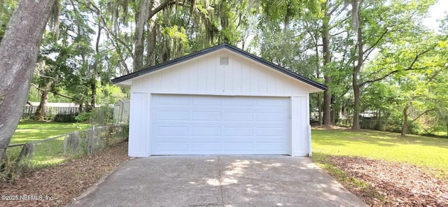 detached garage featuring fence and concrete driveway