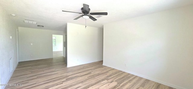 empty room with visible vents, ceiling fan, light wood finished floors, and baseboards