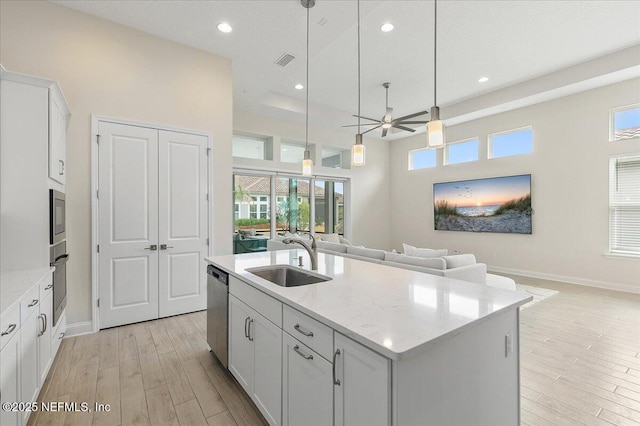 kitchen with a sink, a ceiling fan, light wood-style flooring, appliances with stainless steel finishes, and open floor plan