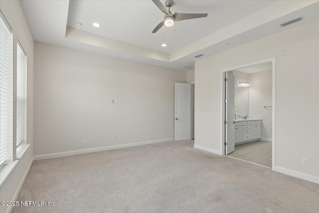 unfurnished bedroom with recessed lighting, a tray ceiling, visible vents, light carpet, and baseboards