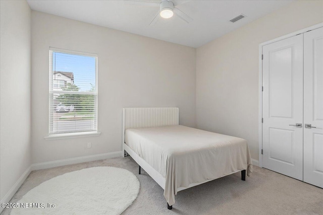 carpeted bedroom featuring a ceiling fan, visible vents, and baseboards