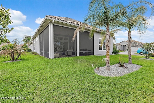 rear view of property featuring stucco siding, a yard, a tile roof, and a sunroom