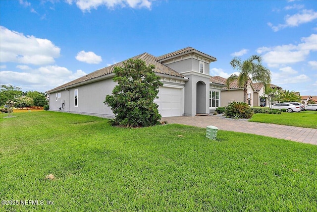 mediterranean / spanish-style house featuring driveway, a tiled roof, stucco siding, a front lawn, and a garage