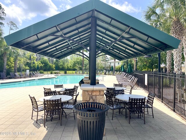 view of patio / terrace with a community pool, fence, and outdoor dining area