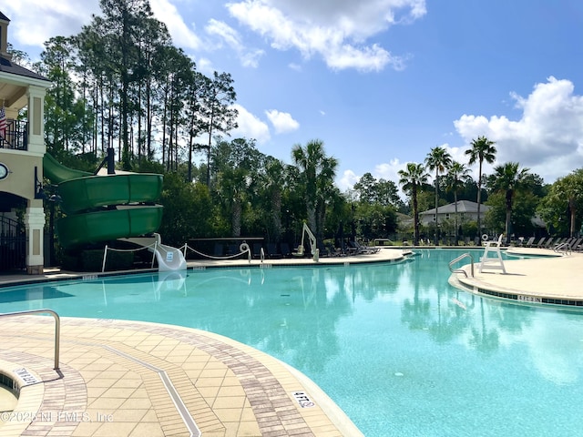 community pool featuring a water slide and a patio area
