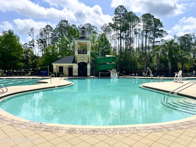 community pool with a patio and a water slide