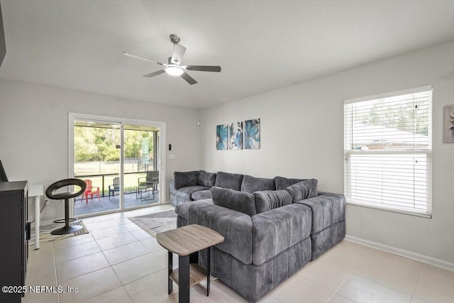 living room with light tile patterned floors, baseboards, and a ceiling fan