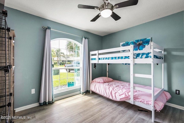 bedroom featuring baseboards, multiple windows, and wood finished floors