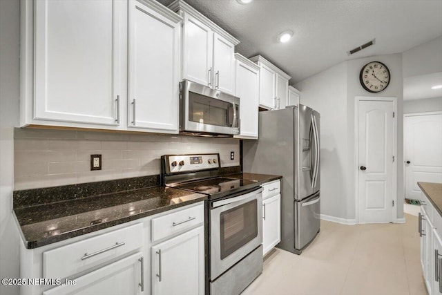 kitchen featuring decorative backsplash, baseboards, dark stone counters, stainless steel appliances, and white cabinetry