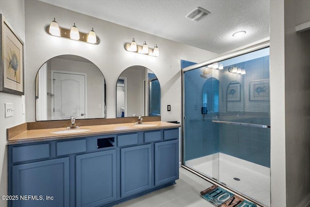 bathroom featuring visible vents, a sink, a textured ceiling, and a stall shower