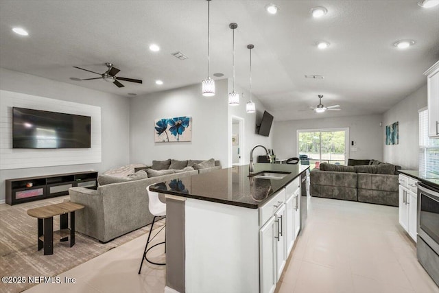 kitchen with ceiling fan, a kitchen bar, appliances with stainless steel finishes, a sink, and open floor plan