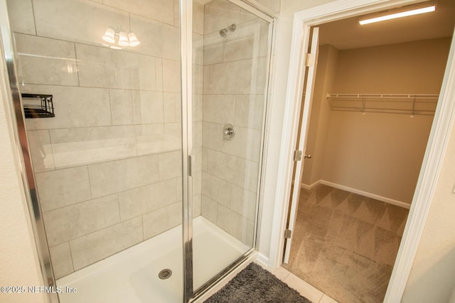 11213 Minnetta Ct, Jacksonville, FL 32256 - bathroom with a stall shower, a walk in closet, tile patterned floors, and baseboards