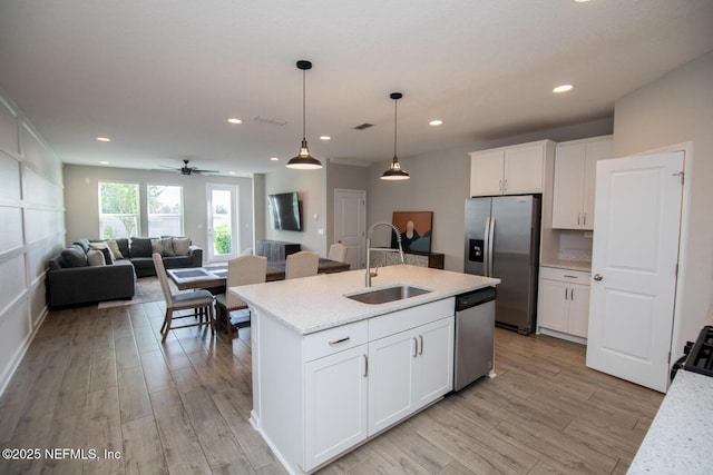 11213 Minnetta Ct, Jacksonville, FL 32256 - kitchen with white cabinets, a sink, appliances with stainless steel finishes, open floor plan, and light wood-type flooring