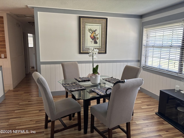 dining room featuring a textured ceiling, wainscoting, and wood finished floors