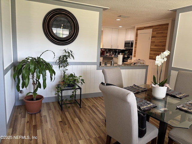 dining area with visible vents, wood finished floors, and a textured ceiling