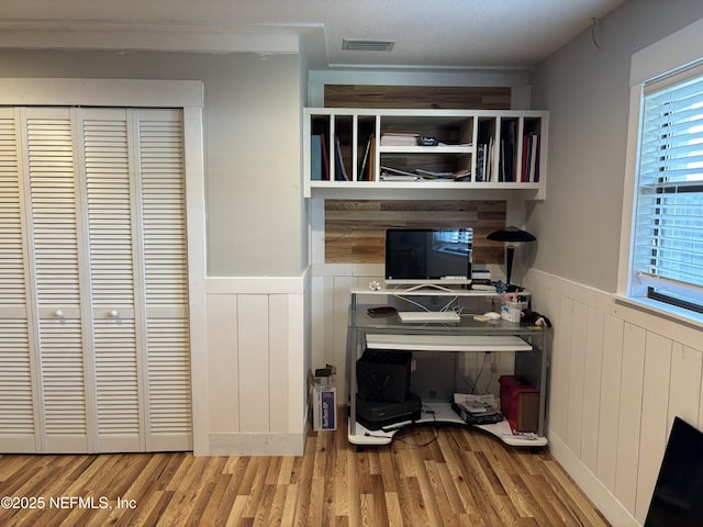 office space featuring visible vents, wainscoting, and wood finished floors