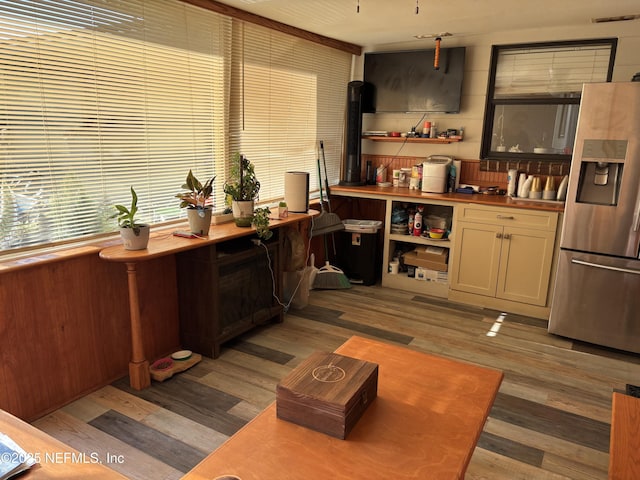bar with visible vents, stainless steel refrigerator with ice dispenser, and light wood-style floors