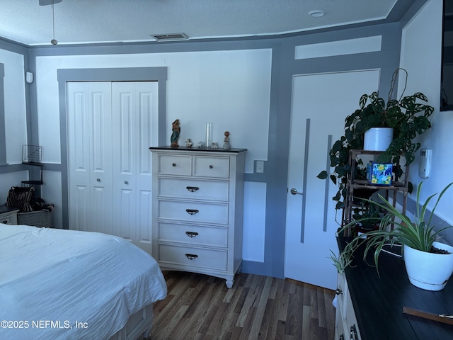 bedroom featuring visible vents, wood finished floors, a textured ceiling, and a closet