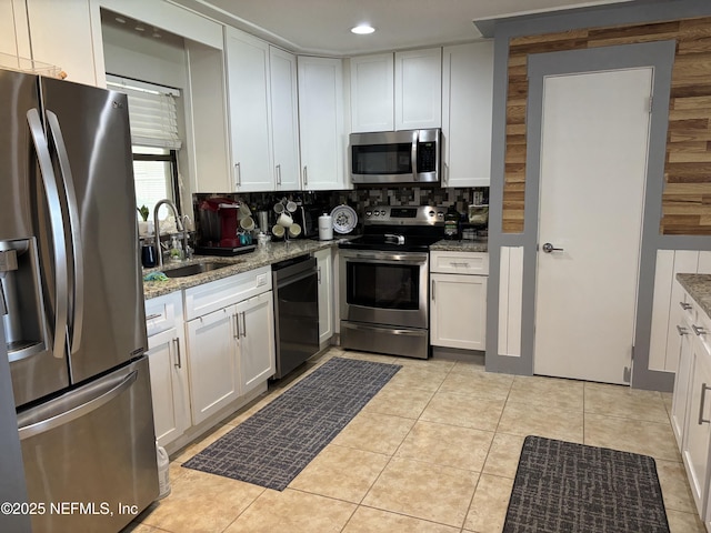 kitchen featuring light stone countertops, a sink, backsplash, and stainless steel appliances