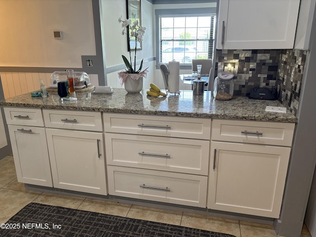 kitchen with white cabinetry, light stone countertops, and light tile patterned floors