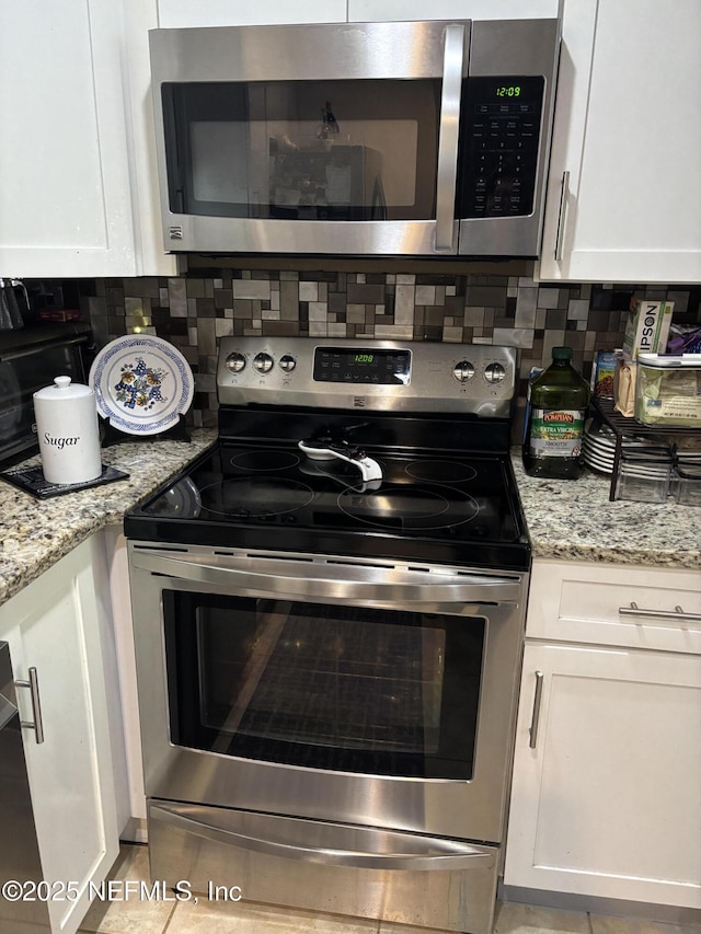 kitchen with appliances with stainless steel finishes, white cabinetry, tasteful backsplash, and light stone counters