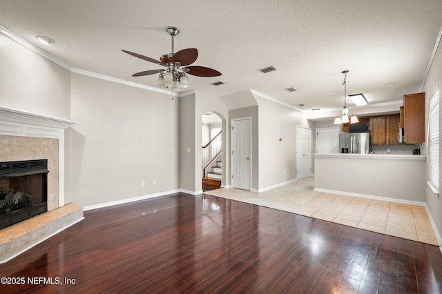 1821 Enterprise Ave, Saint Augustine, FL 32092 - unfurnished living room featuring ceiling fan, a tiled fireplace, light wood finished floors, crown molding, and baseboards