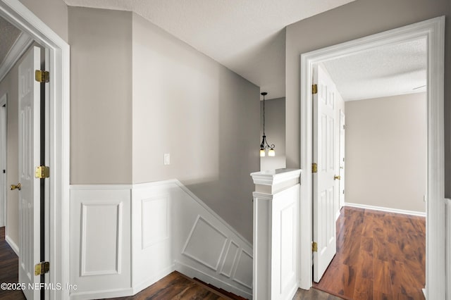 1821 Enterprise Ave, Saint Augustine, FL 32092 - corridor with an upstairs landing, a wainscoted wall, dark wood-style flooring, a decorative wall, and a textured ceiling