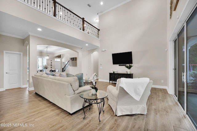 living room with recessed lighting, arched walkways, light wood-style flooring, baseboards, and crown molding