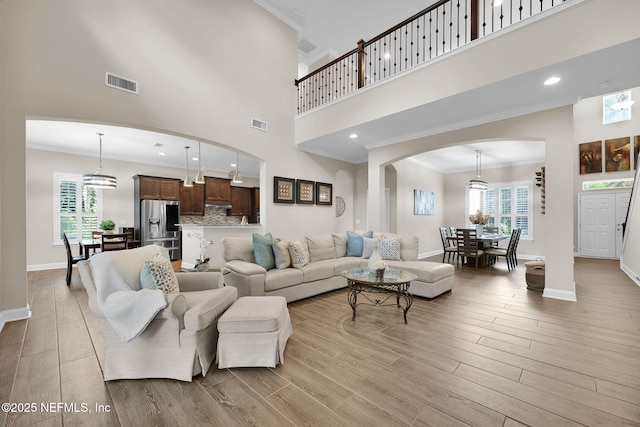 living area with a towering ceiling, arched walkways, visible vents, and plenty of natural light