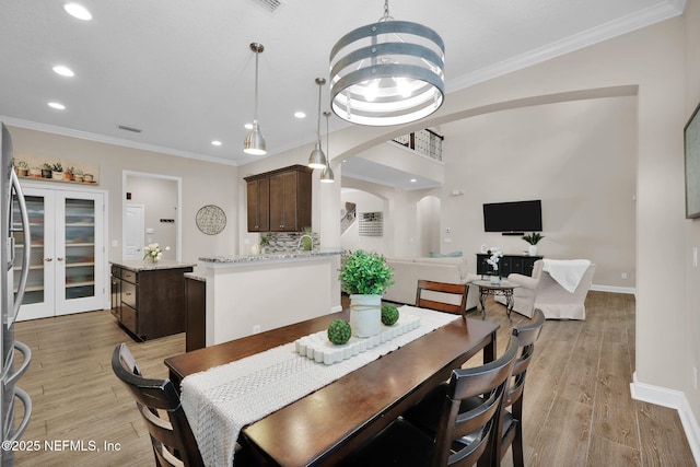 dining area featuring recessed lighting, arched walkways, ornamental molding, baseboards, and light wood-type flooring