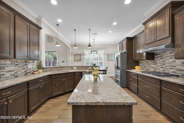 kitchen with a sink, dark brown cabinets, stainless steel appliances, and under cabinet range hood