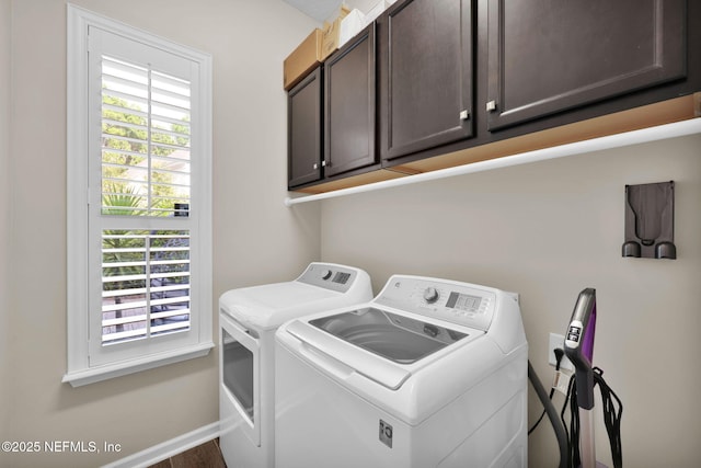 washroom featuring washing machine and clothes dryer, cabinet space, and baseboards