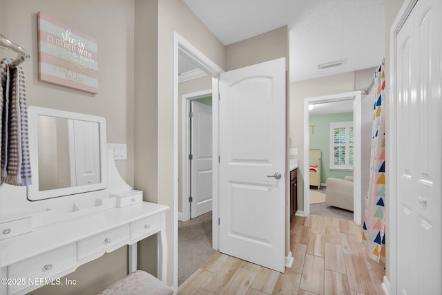 ensuite bathroom featuring ensuite bath, vanity, baseboards, visible vents, and wood finish floors