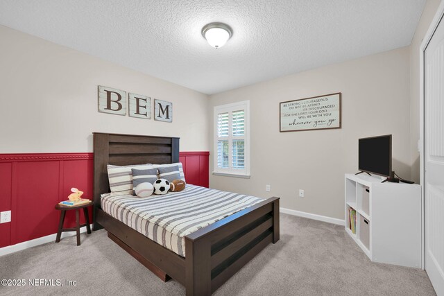 bedroom featuring a wainscoted wall, a textured ceiling, and carpet flooring