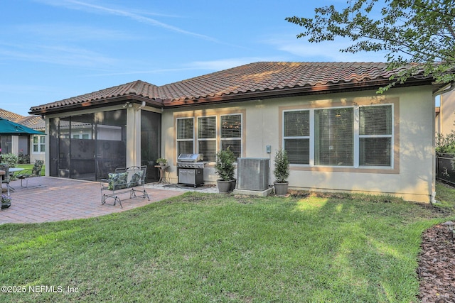 back of property with cooling unit, a patio, a tile roof, a lawn, and a sunroom