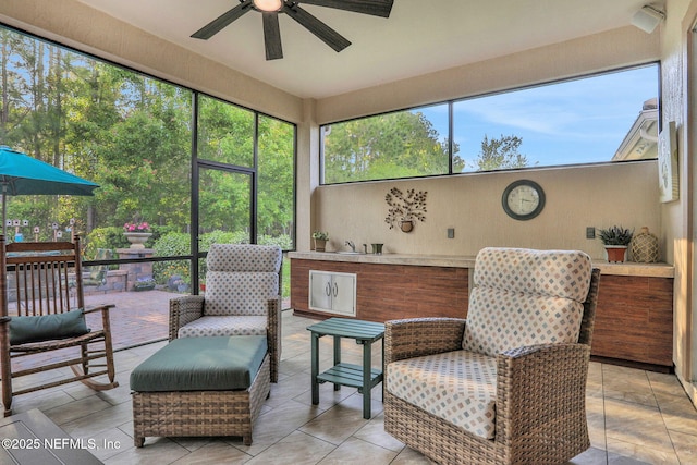sunroom featuring a healthy amount of sunlight, ceiling fan, and an outdoor kitchen